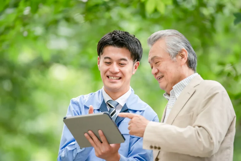 2人の男性がタブレットを眺めながら笑顔で話している