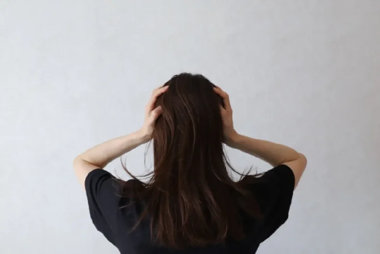 女の人が後ろを向き頭をかかえる