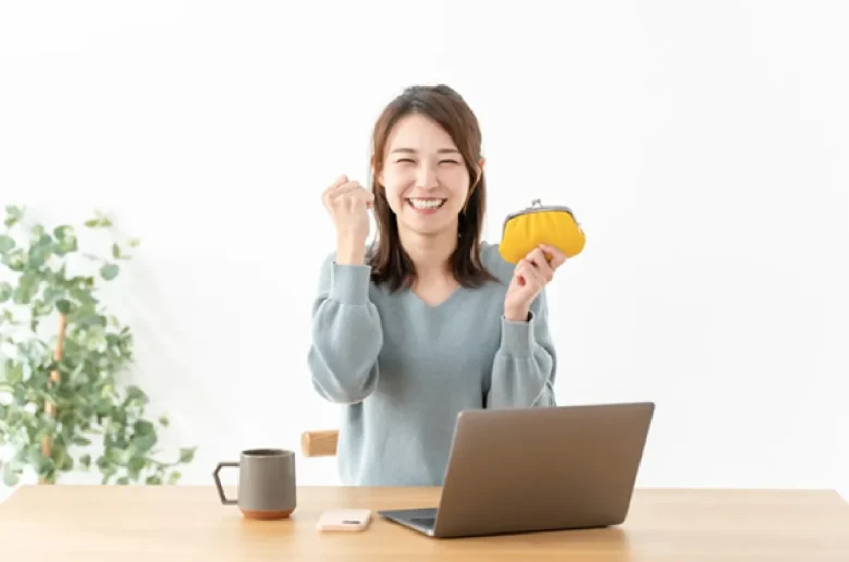 財布を手に笑顔でガッツポーズをする女性