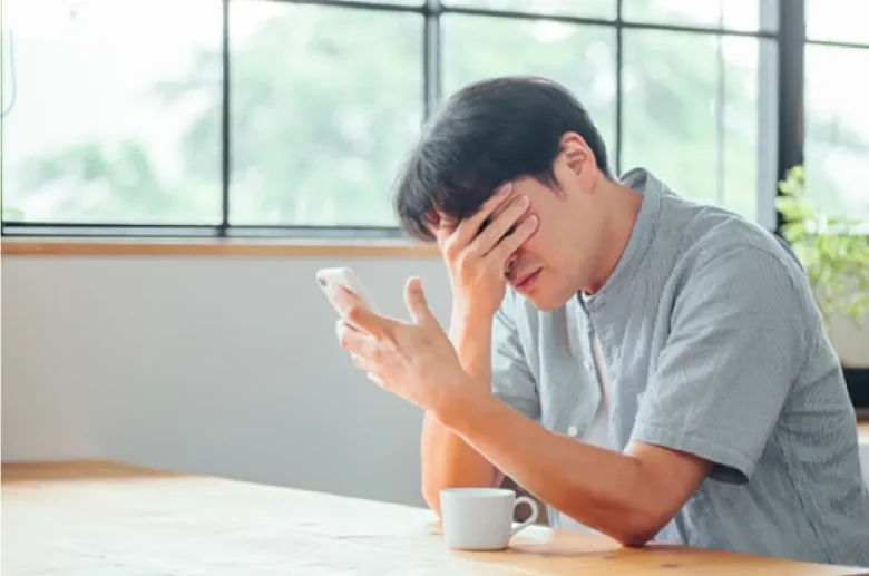 スマホを片手に頭を抱える男性