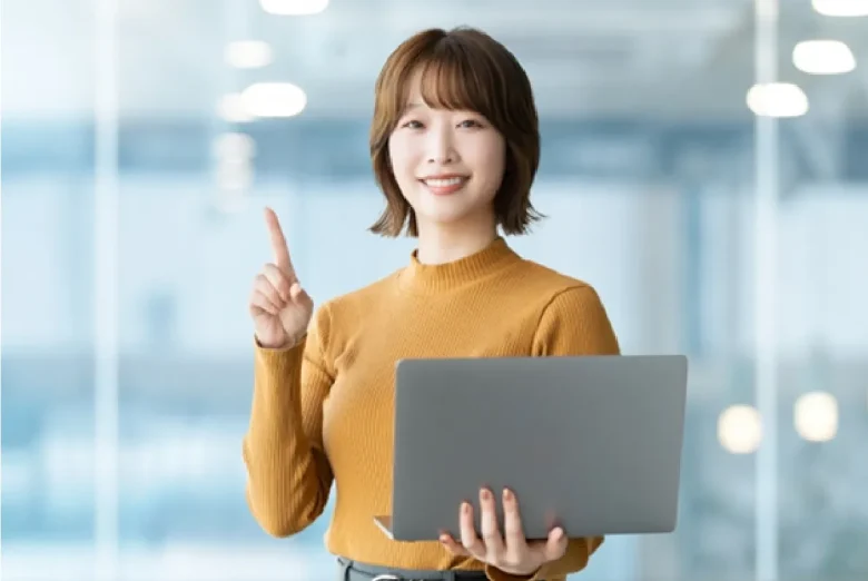 パソコンを持ち人差し指を立てて笑顔な女性