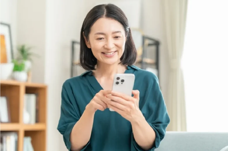 リビングでスマホを見るミドルの女性