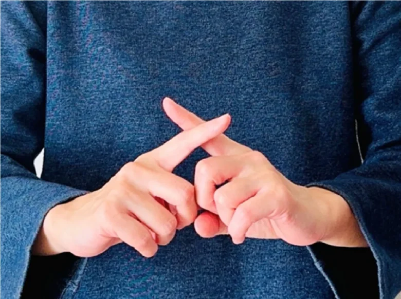 両手の人差し指でバツマークを作る女性