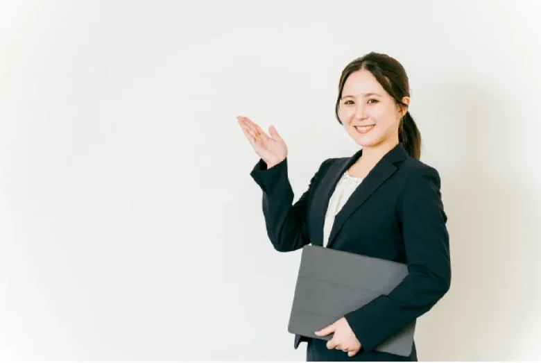 パソコンを小脇に抱え手をあげ笑顔の女性